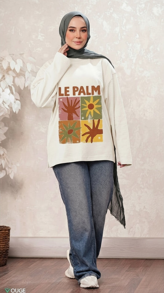 Talla | طلةّ cream long sleeve sweatshirt with retro Le Palm grid graphic, worn by a woman in a sage green hijab and jeans.