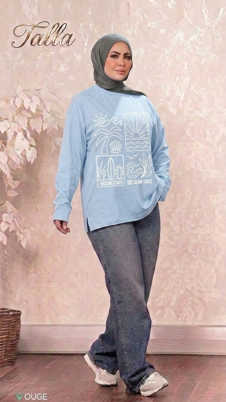 A model wearing a Talla | طلةّ light blue long-sleeve sweatshirt with a white Ocean State graphic print and side slits.