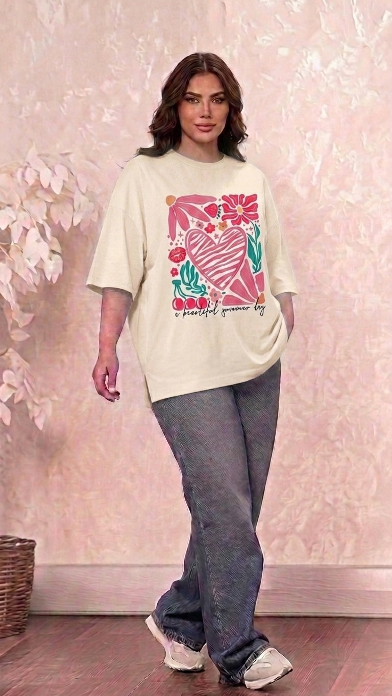 Talla | طلةّ oversized cream t-shirt with a colorful heart, flower, and cherry graphic print worn with dark jeans.