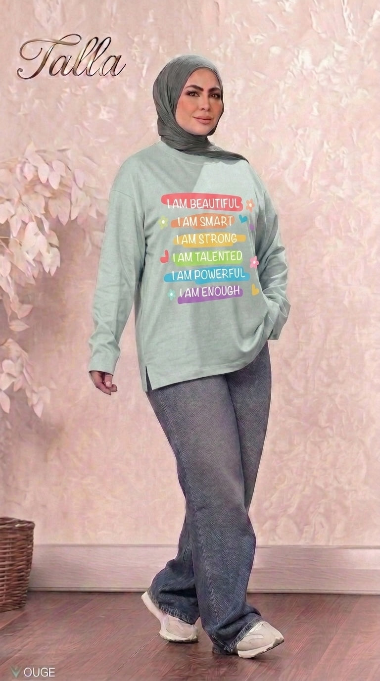 Talla | طلةّ sage green long sleeve sweatshirt with colorful affirmation graphic print worn with grey jeans and hijab