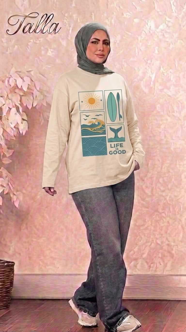 Model wearing a Talla | طلةّ beige long-sleeve sweatshirt with a coastal graphic print, paired with grey jeans.