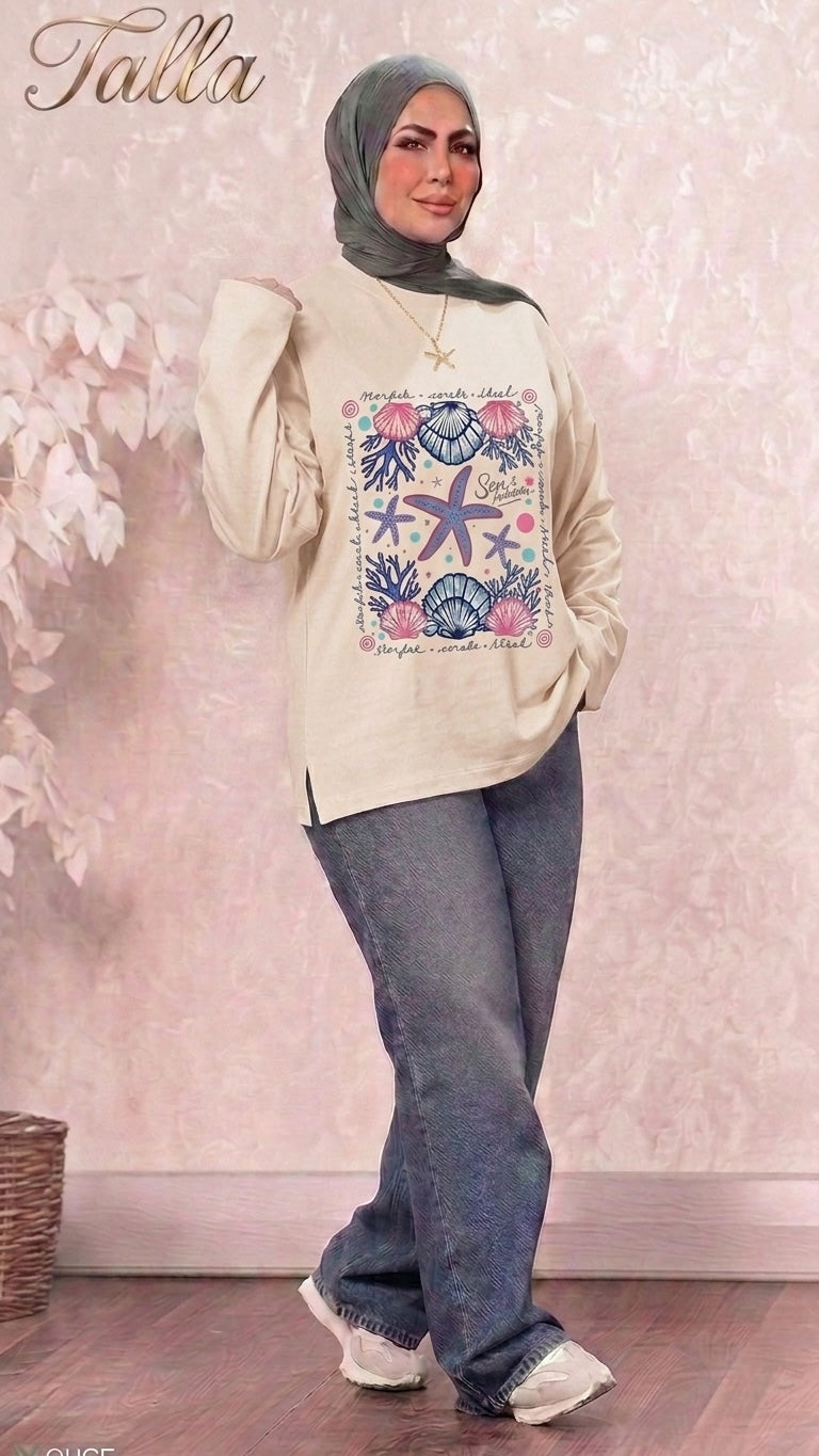 Talla | طلةّ beige long sleeve sweatshirt with a nautical starfish and seashell graphic print, worn with jeans and hijab.