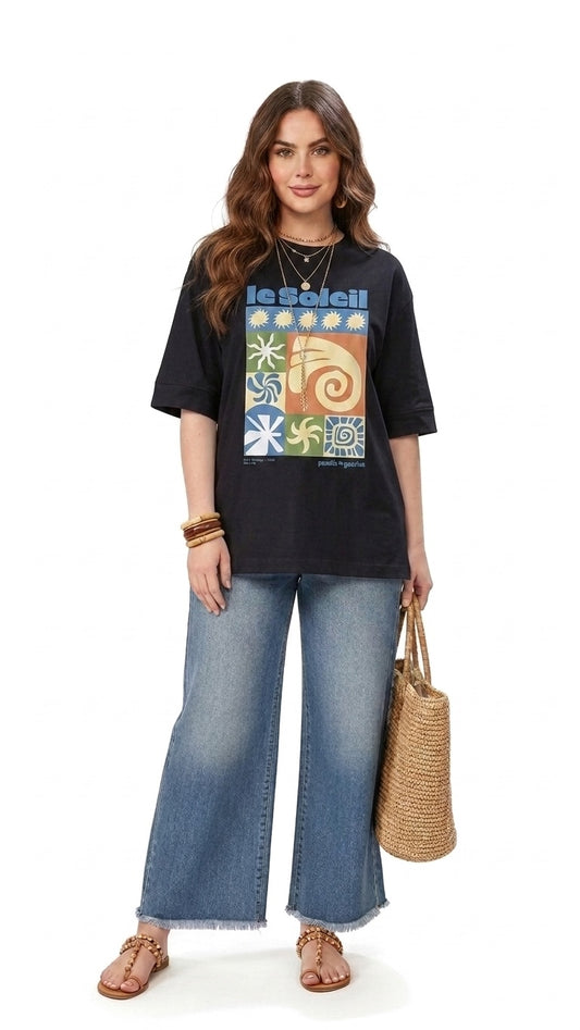 Talla | طلةّ black oversized cotton t-shirt with a colorful sun-inspired graphic print worn by a model with jeans.