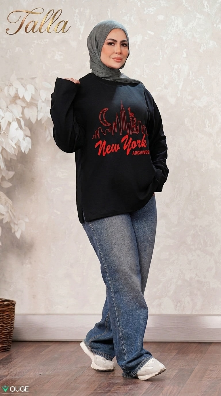 Talla | طلةّ black sweatshirt with red New York skyline graphic, worn by a woman in a grey hijab and blue jeans.