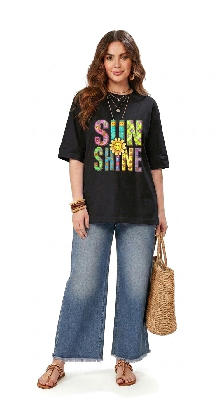 Model wearing a Talla | طلةّ black relaxed-fit graphic tee with a colorful SUNSHINE print and sunflower detail.