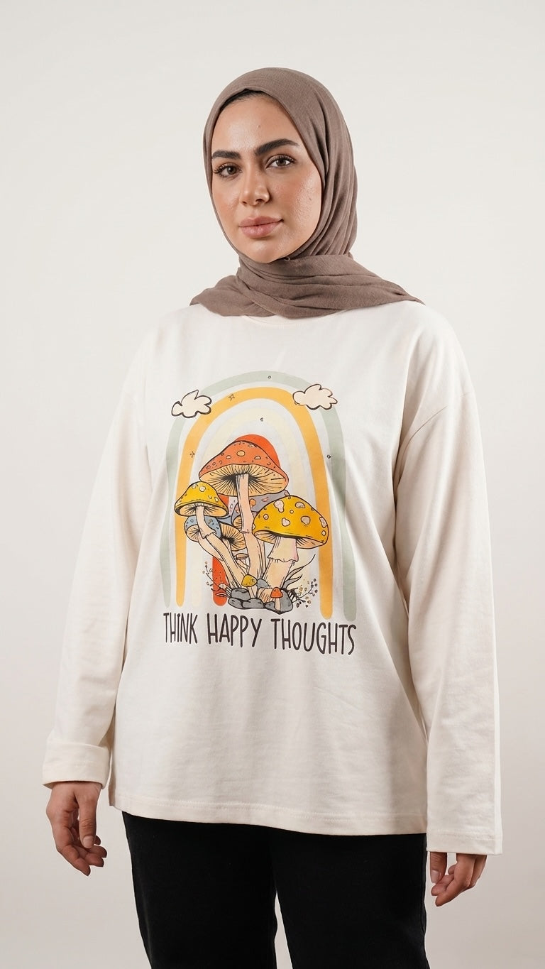 Talla | طلةّ long-sleeve cream cotton tee with a retro mushroom and rainbow graphic print worn by a woman in a hijab.