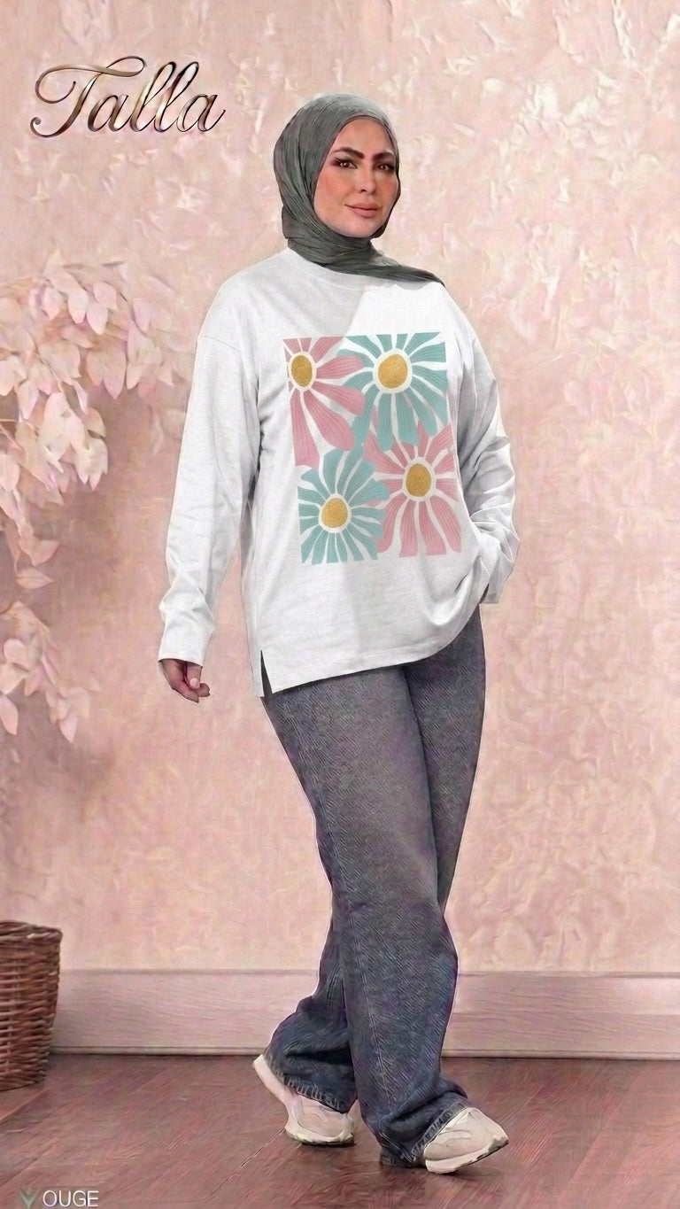 Talla | طلةّ long sleeve sweatshirt in white with a floral graphic print, worn by a woman in a grey hijab and jeans.