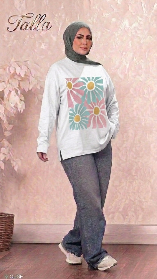 Talla | طلةّ long sleeve sweatshirt in white with a floral graphic print, worn by a woman in a grey hijab and jeans.