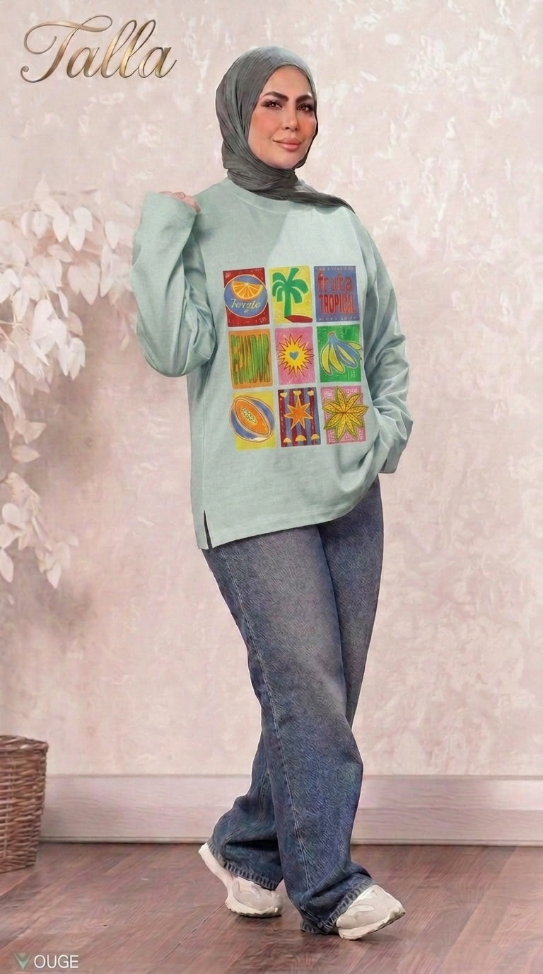 Talla | طلةّ light green long sleeve sweatshirt with a tropical fruit grid graphic print worn with blue jeans and hijab