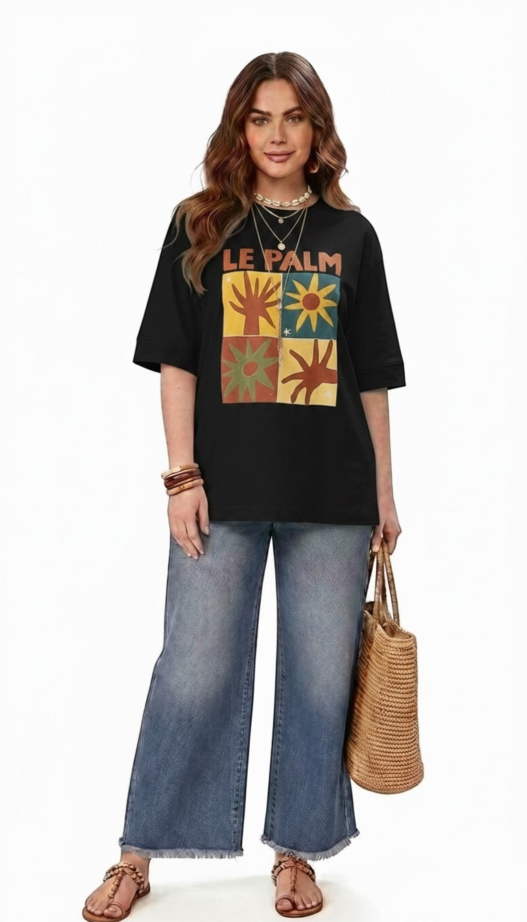 Talla | طلةّ Le Palm black oversized cotton t-shirt with a vibrant sun and palm tree graphic print on a female model.