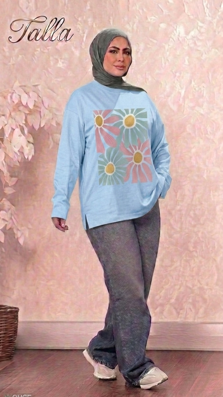 Talla | طلةّ light blue long sleeve sweatshirt with a floral graphic print, worn by a woman in a hijab and jeans.