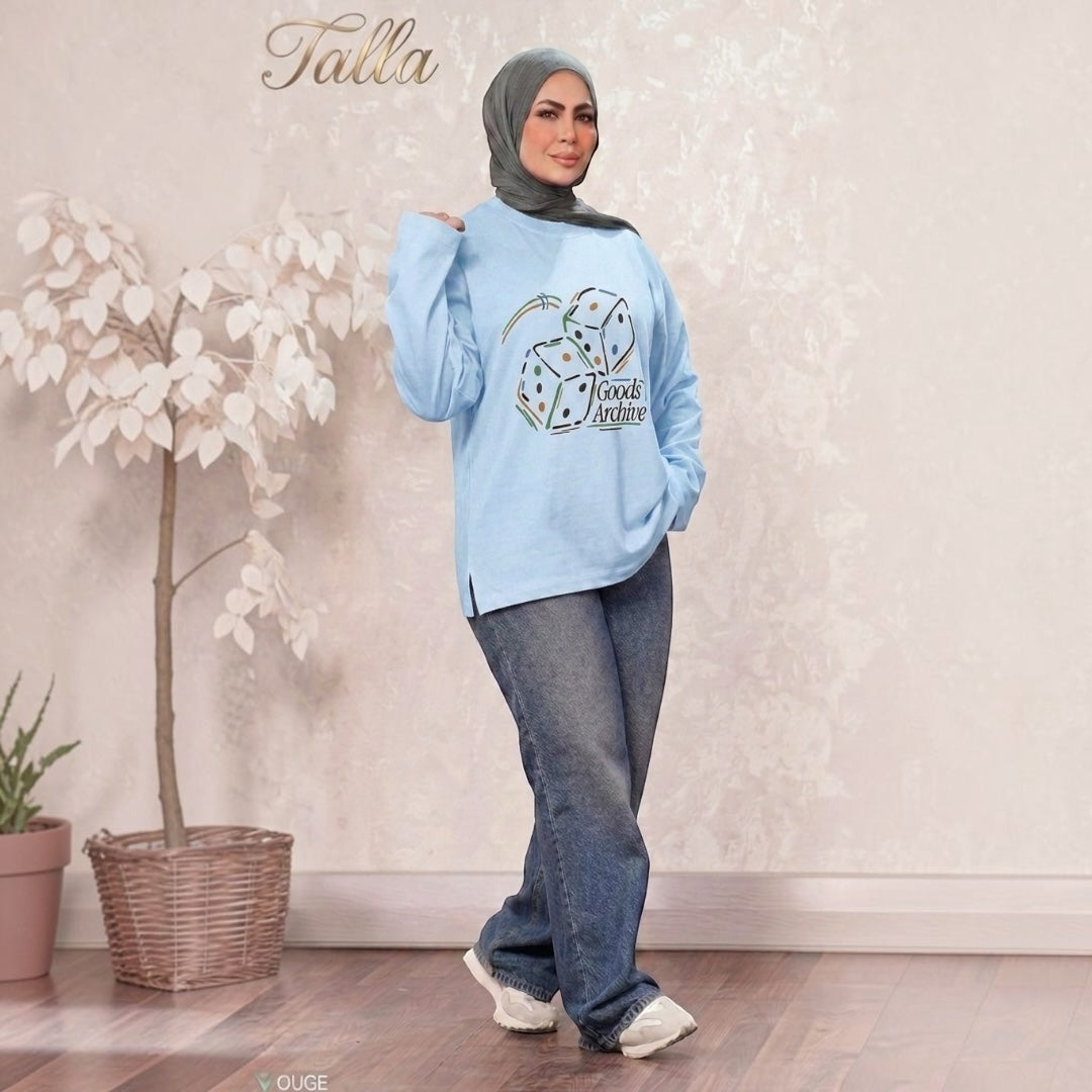 Talla | طلةّ light blue graphic sweatshirt with Goods Archive dice print, worn by a woman in a hijab and jeans.