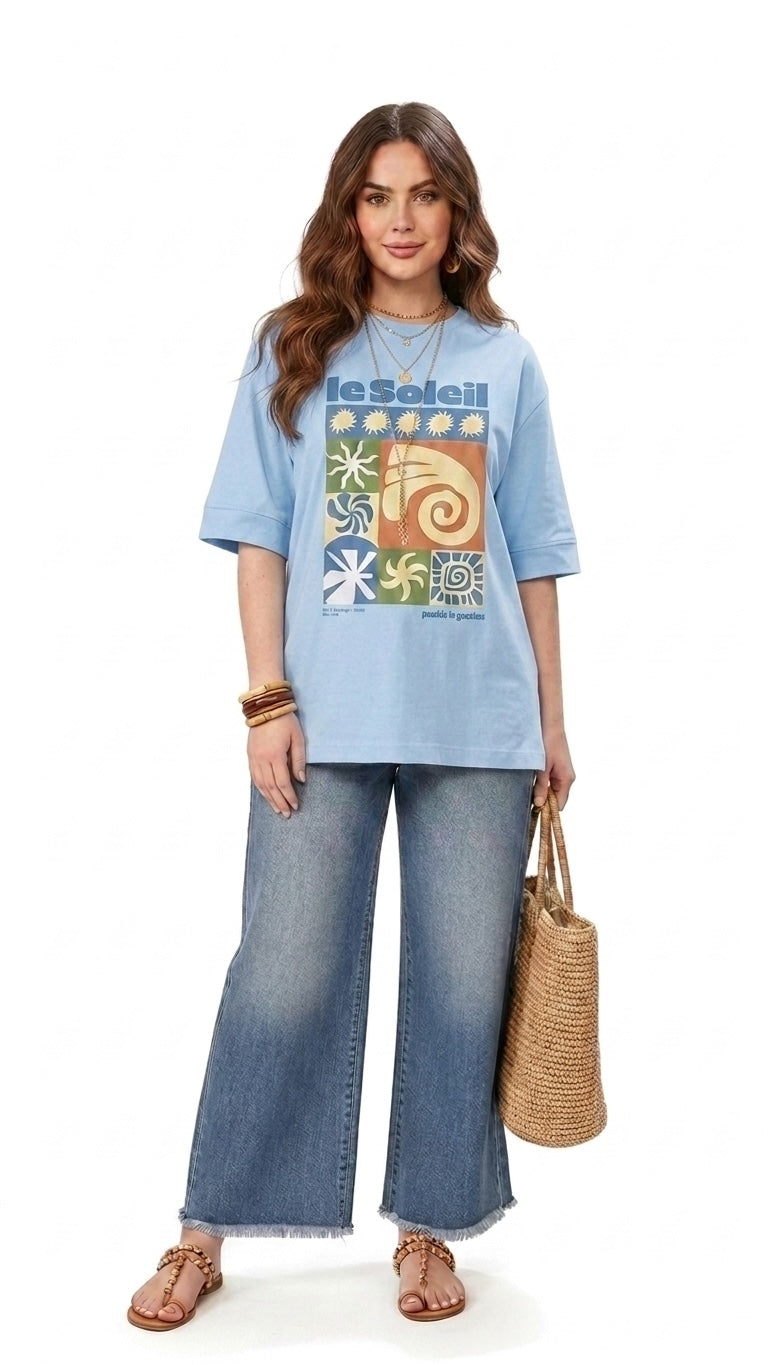 Talla | طلةّ light blue oversized cotton t-shirt with a vibrant sun-inspired graphic print and elbow-length sleeves.