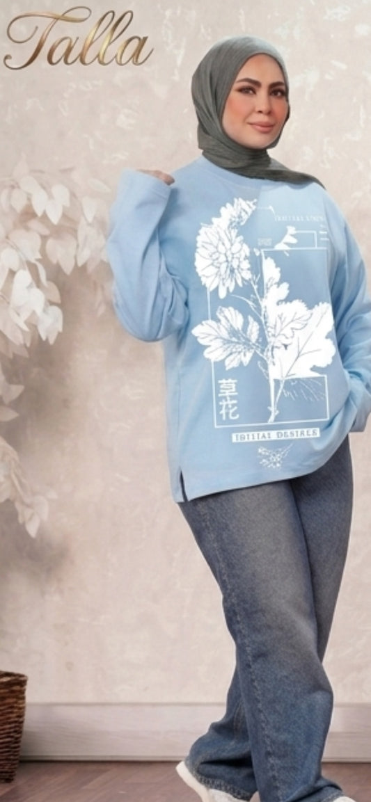 Talla | طلةّ light blue cotton top with white floral graphic print and side slits worn with jeans and a hijab