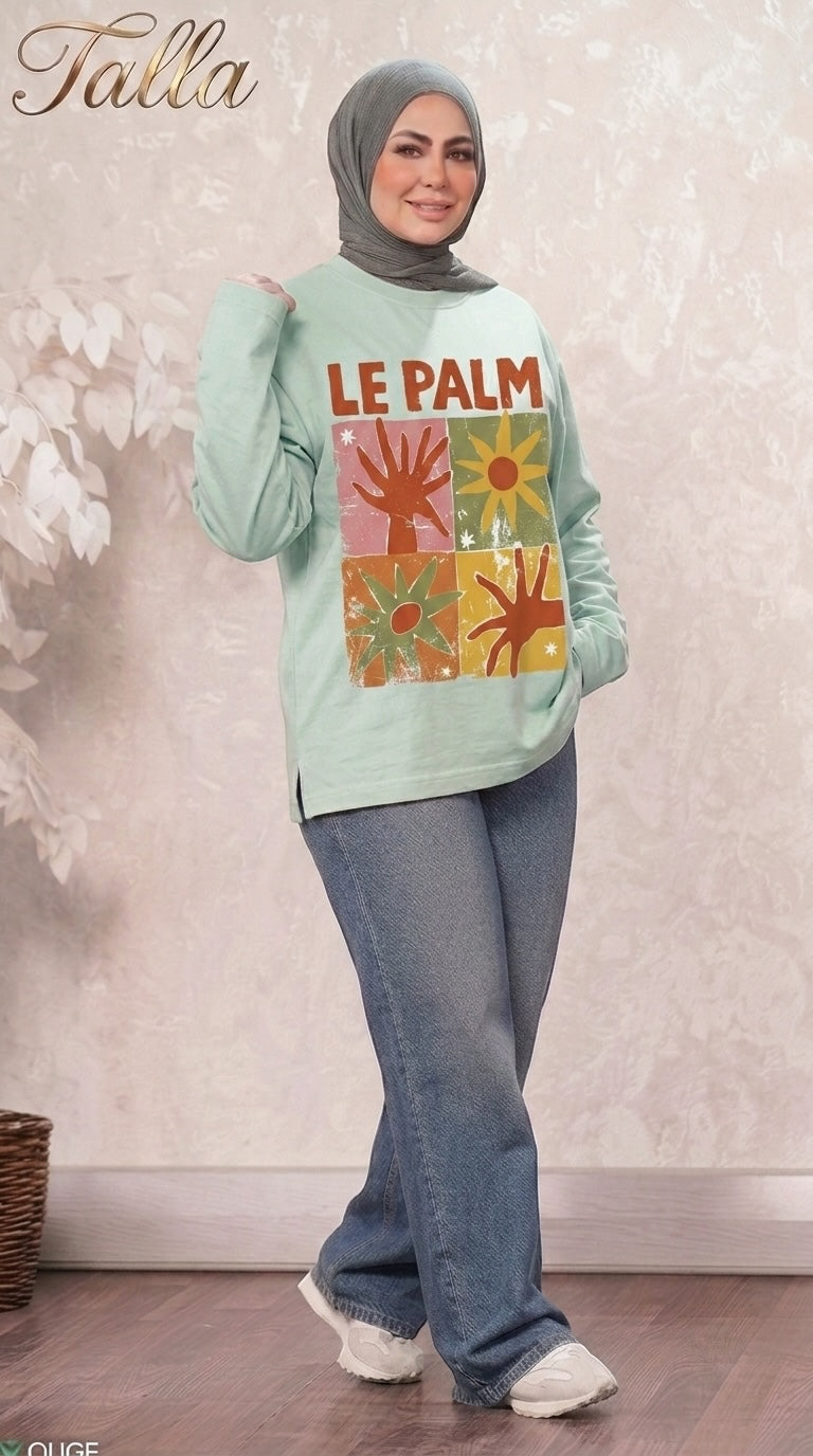 Talla | طلةّ mint green long sleeve sweatshirt with Le Palm graphic print, crew neck, and side-slit hem worn by a model.
