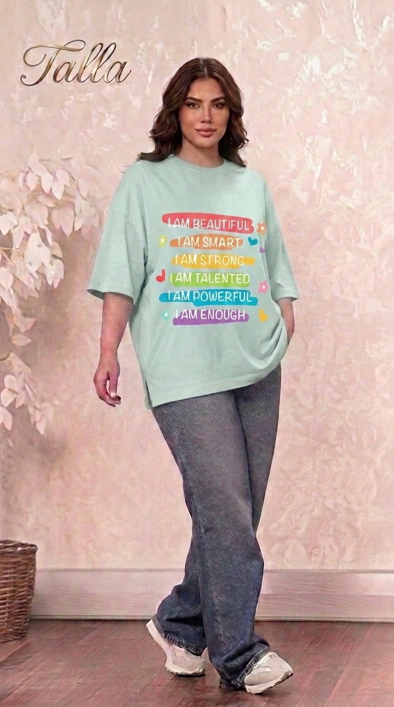Model wearing a Talla | طلةّ oversized mint green cotton t-shirt with a colorful inspirational graphic print and side slits.