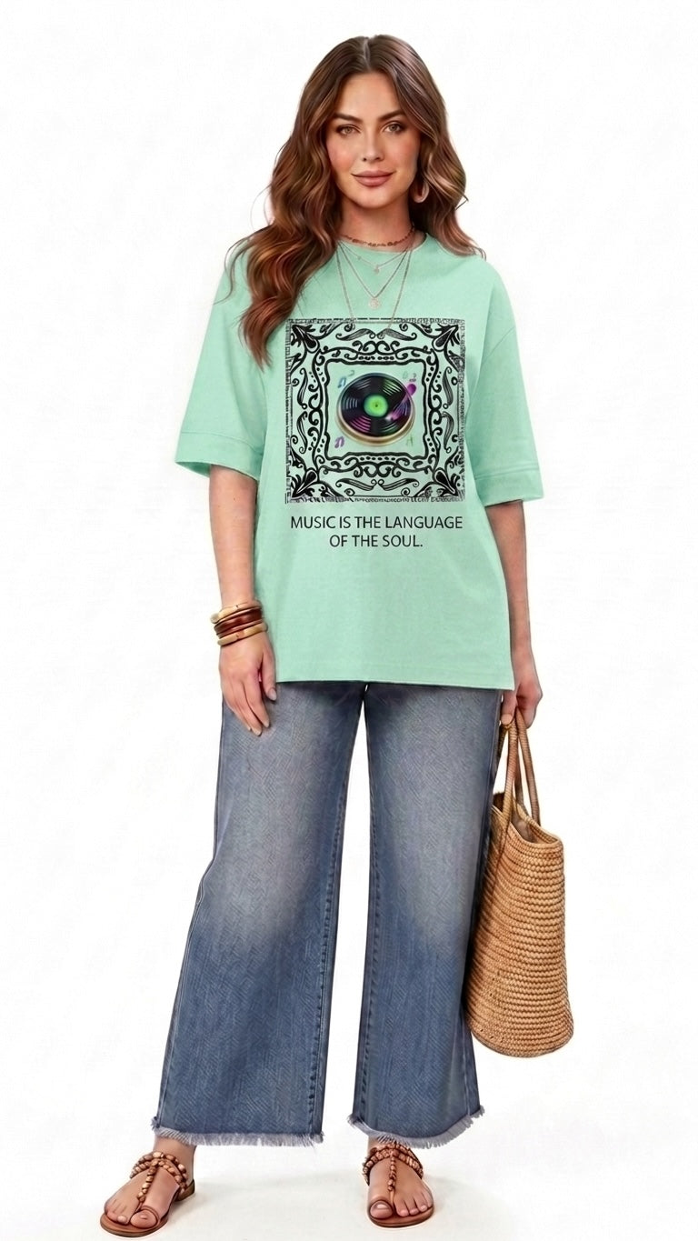 Model wearing a mint green Talla | طلةّ oversized graphic t-shirt with a record player print and music slogan.