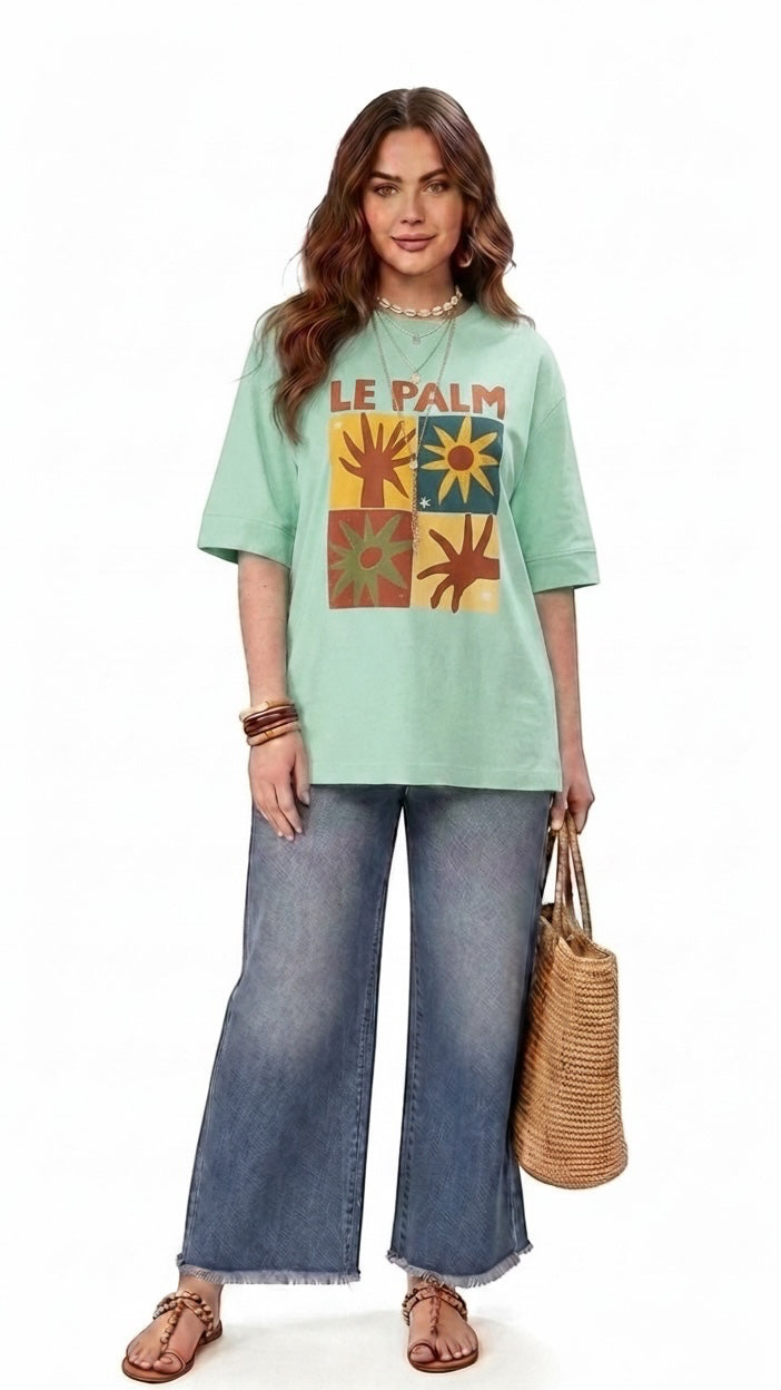 Talla | طلةّ oversized mint green cotton t-shirt with a multi-paneled sun and palm graphic print worn by a woman.