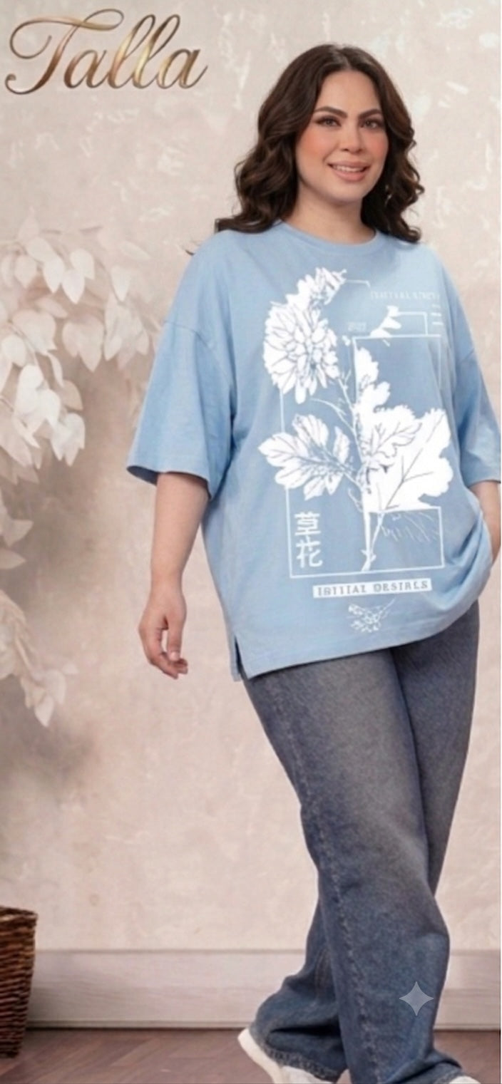Talla | طلةّ oversized light blue t-shirt with white floral graphic print and side slits worn by a smiling woman