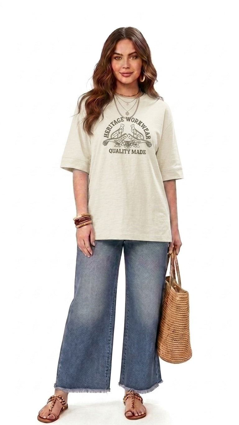 Talla | طلةّ oversized beige cotton t-shirt with vintage graphic print, worn by a woman with wide-leg jeans and sandals.