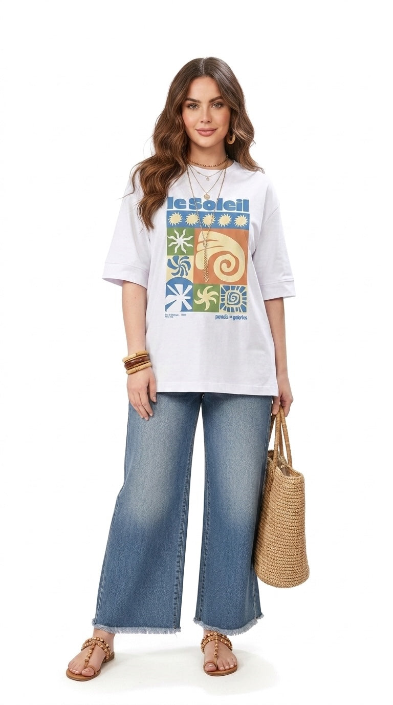 Talla | طلةّ oversized white cotton t-shirt with a colorful sun-inspired graphic print worn with wide-leg jeans.
