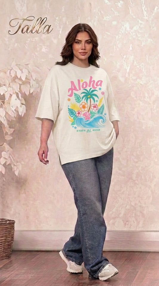 Talla | طلةّ oversized cream t-shirt with tropical Aloha graphic print, worn by a woman with dark hair and blue jeans.