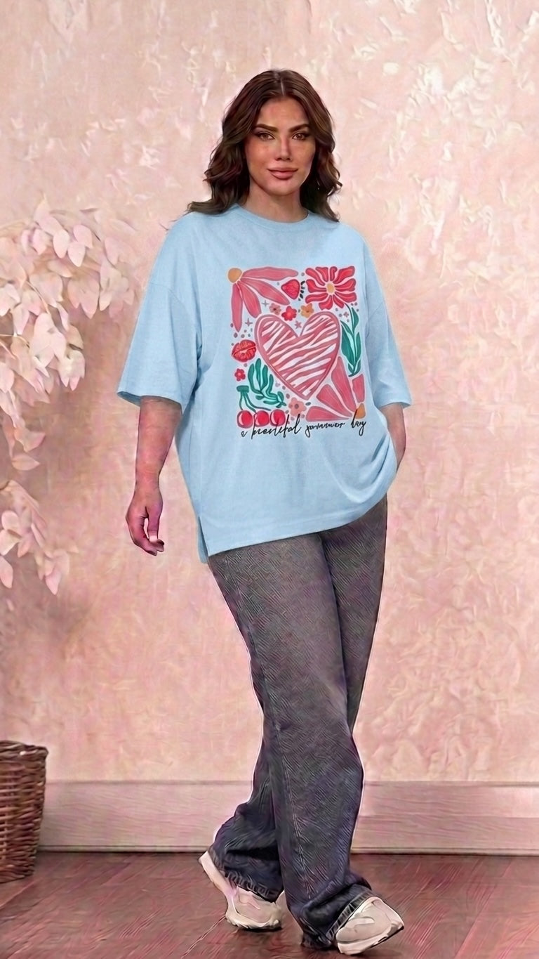 Talla | طلةّ oversized light blue t-shirt featuring a heart, flower, and cherry graphic print worn by a woman.