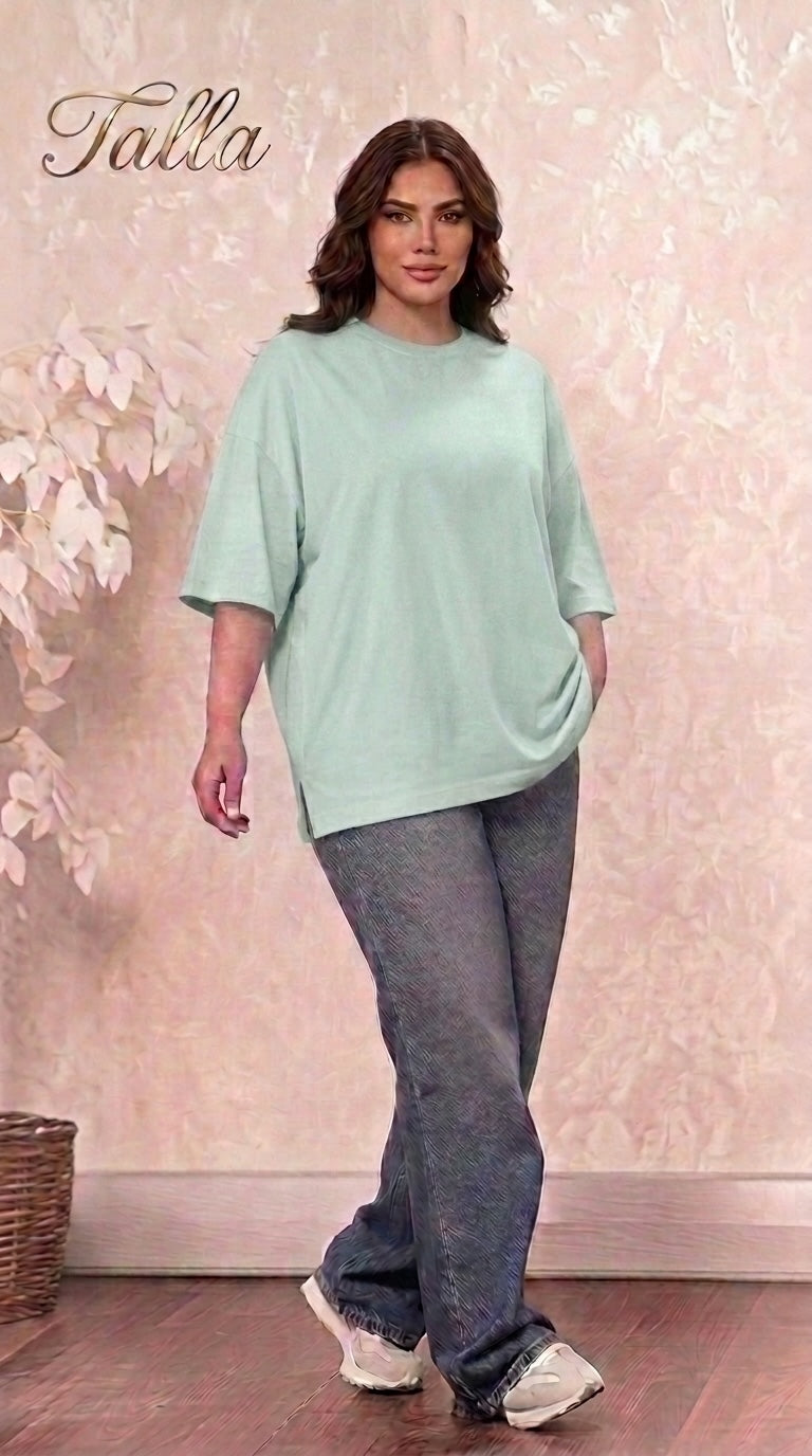 A model wearing a Talla | طلةّ oversized mint green cotton crewneck t-shirt with side slits and relaxed-fit jeans.