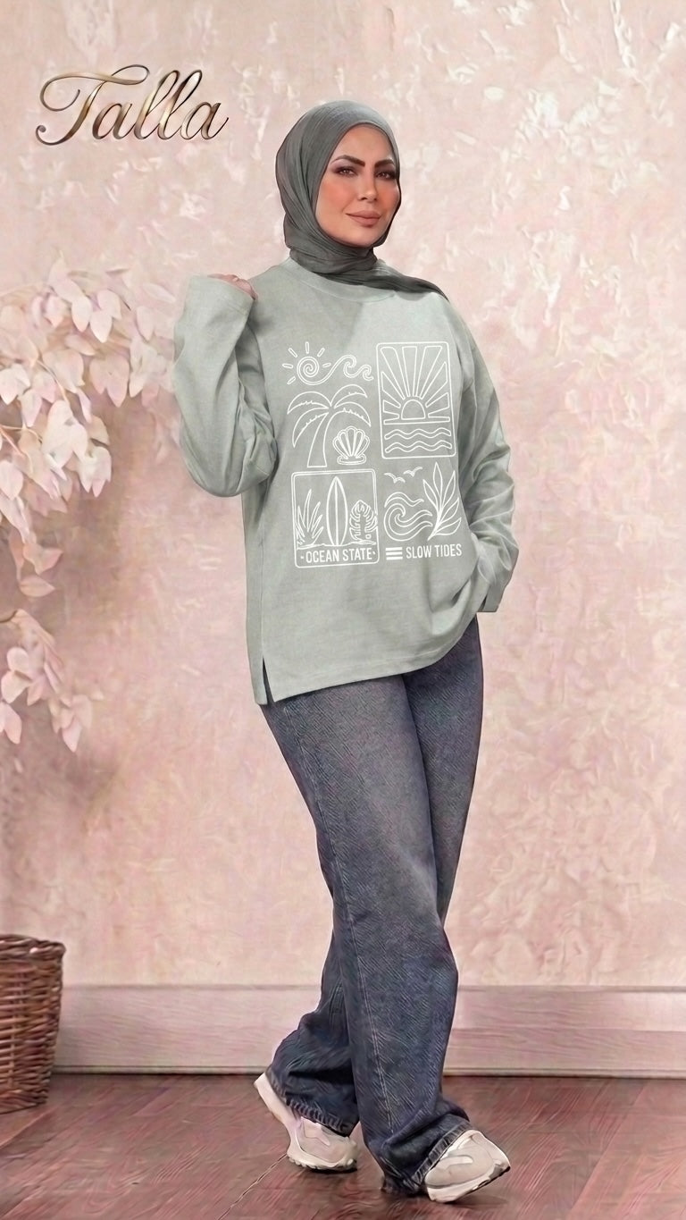 Talla | طلةّ sage green long sleeve sweatshirt with Ocean State graphic print, worn by a model with a grey hijab.